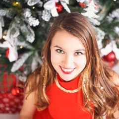 Portrait of beautiful sweet young woman in gorgeous evening dress over Christmas background.