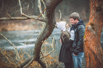 Beautiful young couple posing near lake and forest autumn. Woman in white gloves and cap.