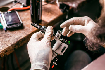 The tattoo artist holding a machine for tattoo