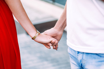 man in light clothing holding his woman in a red dress by her ha