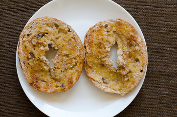 Two halves of a toasted raisin bagel with butter