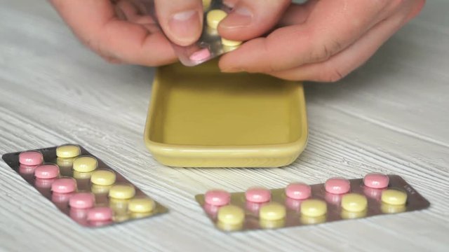 Man's hand pulls out the pills from a blister card