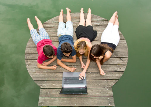 Gruppe Jugendliche mit Notebook / Laptop draußen in der Natur