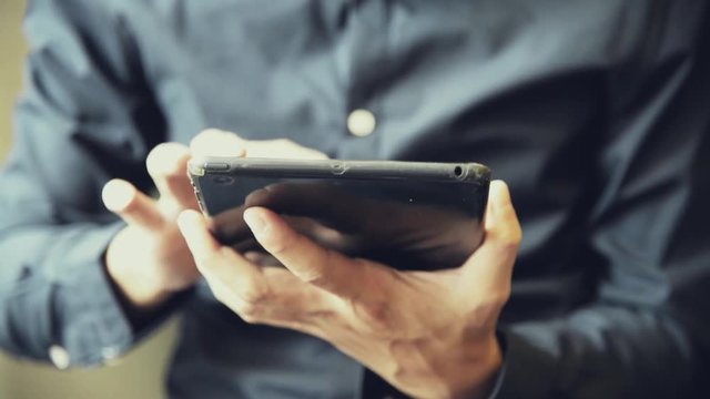 Handsome Asian male use tablet with touch screen to connect to the internet cinematic tone full HD