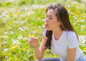 Woman blowing dandelion in park 