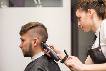 young man cuts hair in the barber shop