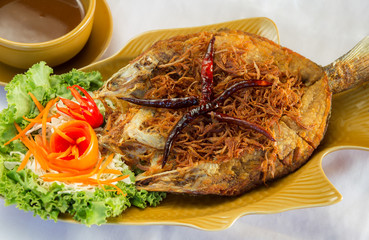Fried fish topped with chili, vegetable dish.