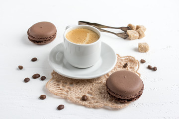 Coffee Cup and chocolate French macaroons on a white wooden back