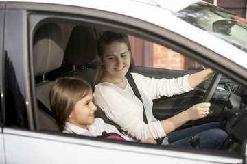 Young mother driving car to school with daughter