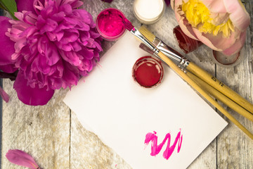 Workspace. Watercolor, paintbrush and pink peonies isolated on white background. Overhead view. Flat lay, top view