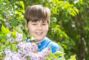 Portrait of boy in park with blooming lilacs