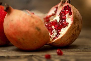 Macro shot of pomegranate two halves lying on old wooden desk