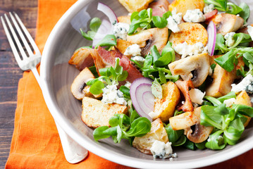 Potato salad with bacon, mushroom on orange napkin.