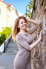 Obraz premium Young fashion woman in dress near stone wall. City lifestyle. Female fashion.