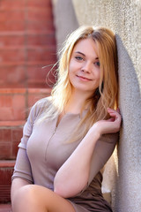 Young fashion woman in dress near stone wall.  City lifestyle. Female fashion.