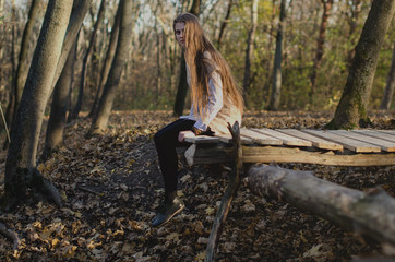 Girl sitting on wood construction in forest