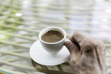 Senior Turkish woman hand holding a cup of Turkish coffee on a g