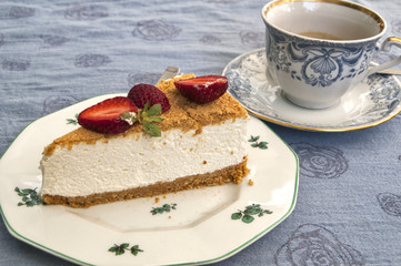 Piece of cheesecake in porcelain saucer and cup of coffee