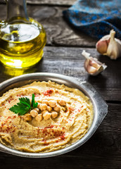 Hummus in metal bowl on  wooden table.