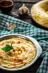 Hummus in metal bowl on  wooden table.