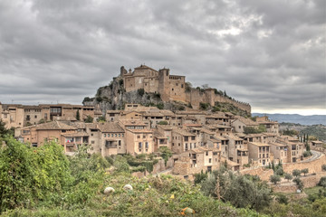 Fototapeta na wymiar Vista de la villa medieval de Alquezar bajo un cielo nublado y unes calabazas en primer termino.