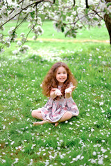 Naklejka na ściany i meble Little curly baby in blossom garden