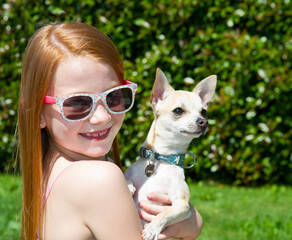 a cute toddler girl with colored  sunglasses on holding her little dog