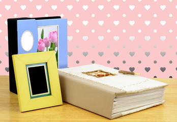 Photo frame and albums on pink background.
