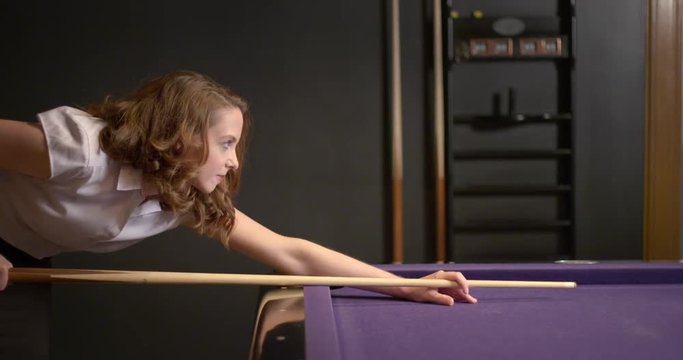 Young business woman plays billiards in a relaxed lounge setting.  Slow motion medium shot recorded at 60fps.