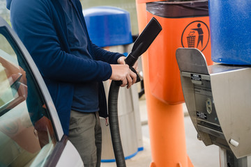 Person using self service automatic car wash vacuum machine. 