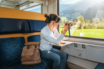 Woman traveler photographed through a train window. Beautiful views from the windows. Traveling by train at the Alpine Railroad