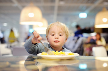 Toddler boy eating in indoors cafe