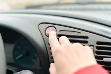 Young lady pressing emergency button on car sport dashboard.Closeup 