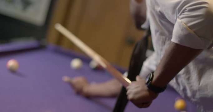 African American business man relaxes by playing pool.  Extreme angle with shallow focus, recorded in slow motion at 60fps.