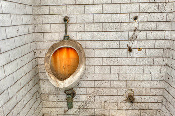 Filthy, stained urinal in the toilet of an abandoned prison. - obrazy, fototapety, plakaty