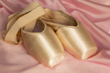 Ballet shoes on delicate pink silk background