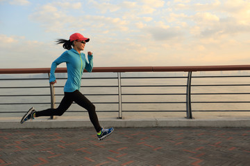 young fitness woman runner running on seaside road