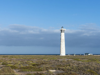 Fototapeta na wymiar White puristic lighthouse blue sky.