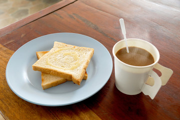 Fototapeta na wymiar Hot coffee and bread toast topped with milk for breakfast on woo
