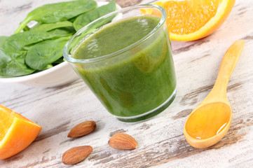 Ingredients and fresh cocktail from spinach on wooden background, healthy nutrition