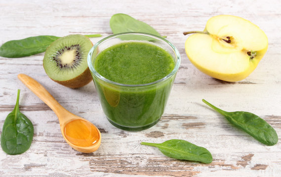 Cocktail from spinach, apple and kiwi with honey on wooden background, healthy nutrition