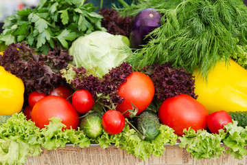 Cucumbers, tomatoes, cabbage, apples, peppers and greens. Various vegetables and fruits in a street market