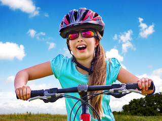 Bikes bicycling child. Girl rides bicycle. Girl wearing sport colored sunglasses. Cyclist look up.