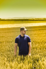 Naklejka na ściany i meble Young farmer on field of wheat