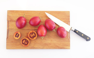 Tamarillos on a wooden chopping board with a knife, photographed from above