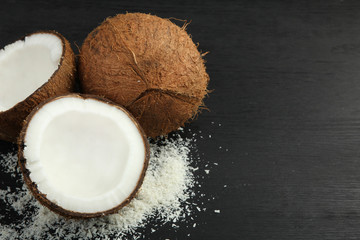 cut coconut with coconut flakes on black wooden background