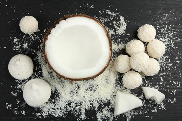 half coconut with coconut candies on a black wooden background