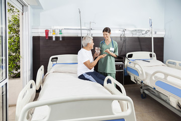 Nurse Giving Medicine And Water To Patient In Rehabilitation Cen