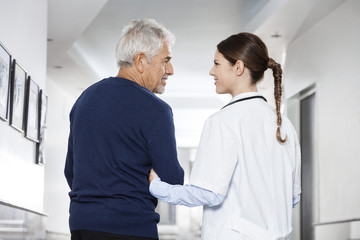Female Doctor Holding Senior Man's Arm In Rehab Center
