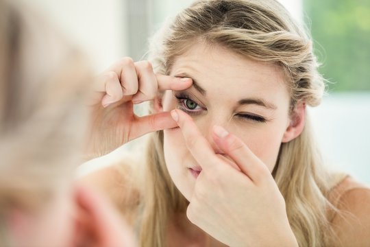 Young woman applying contact lens